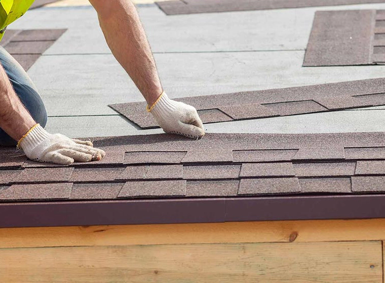 worker adding some brown greyish tiles on the roofing