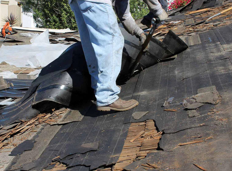 worker repairing a roof with black tiles